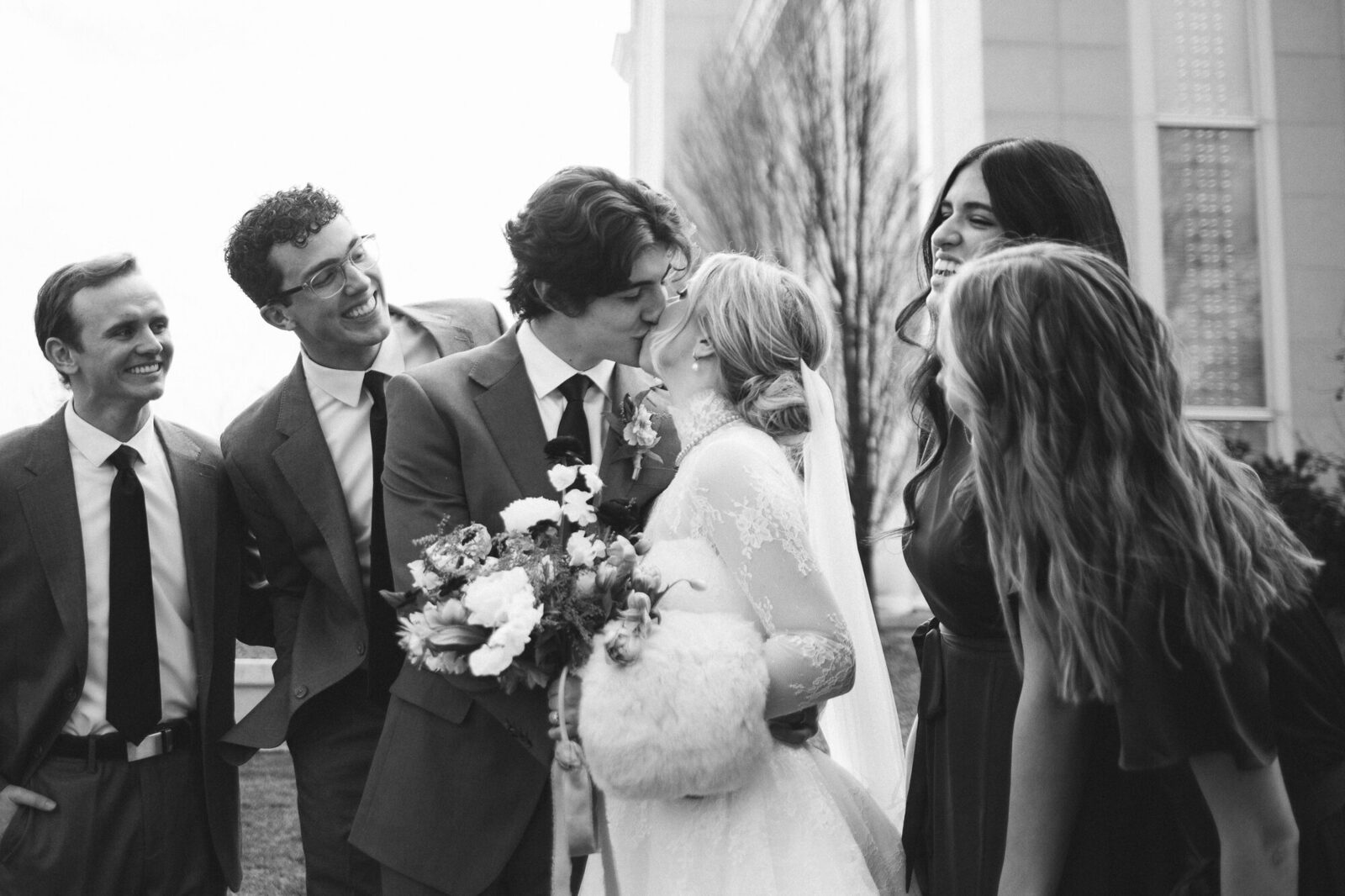 Elle and Braden sharing a kiss surrounded by their wedding party